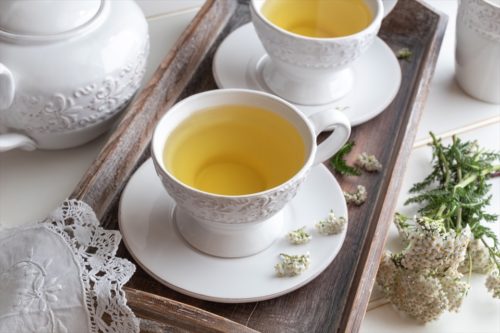 Herbal tea in white vintage cups with fresh yarrow flowers